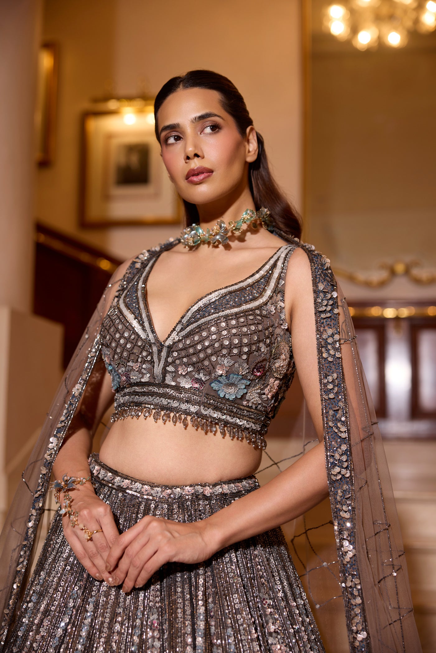 Intricately embroidered grey lehenga with silver sequins and floral motifs, worn with sheer shoulder drapes