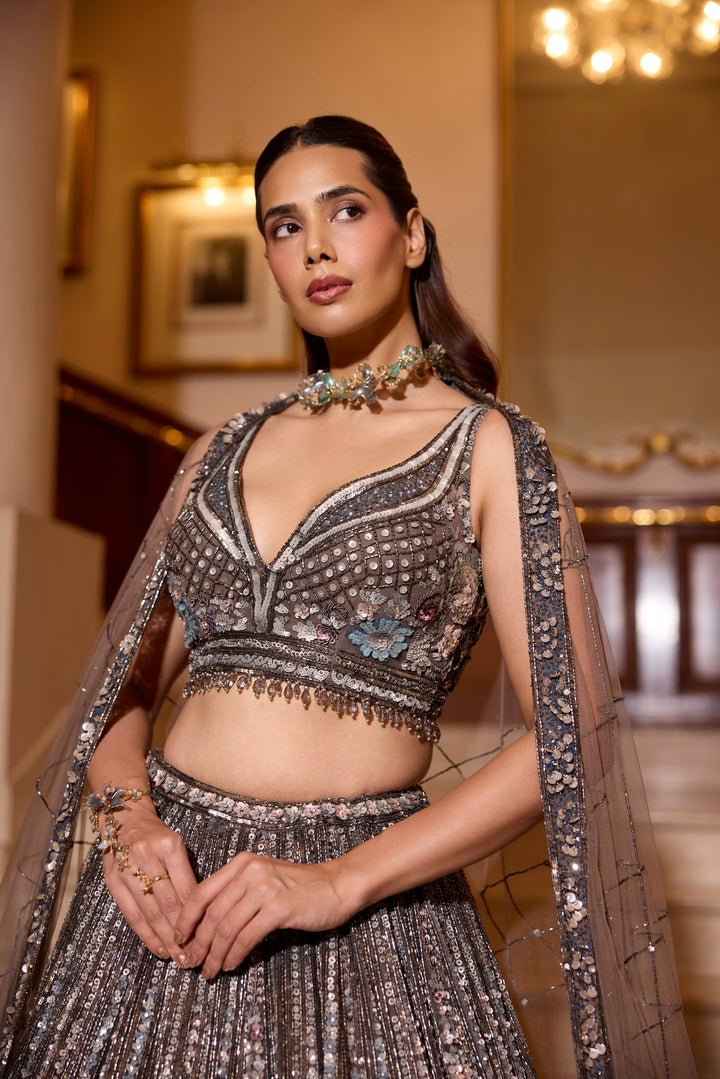 Intricately embroidered grey lehenga with silver sequins and floral motifs, worn with sheer shoulder drapes